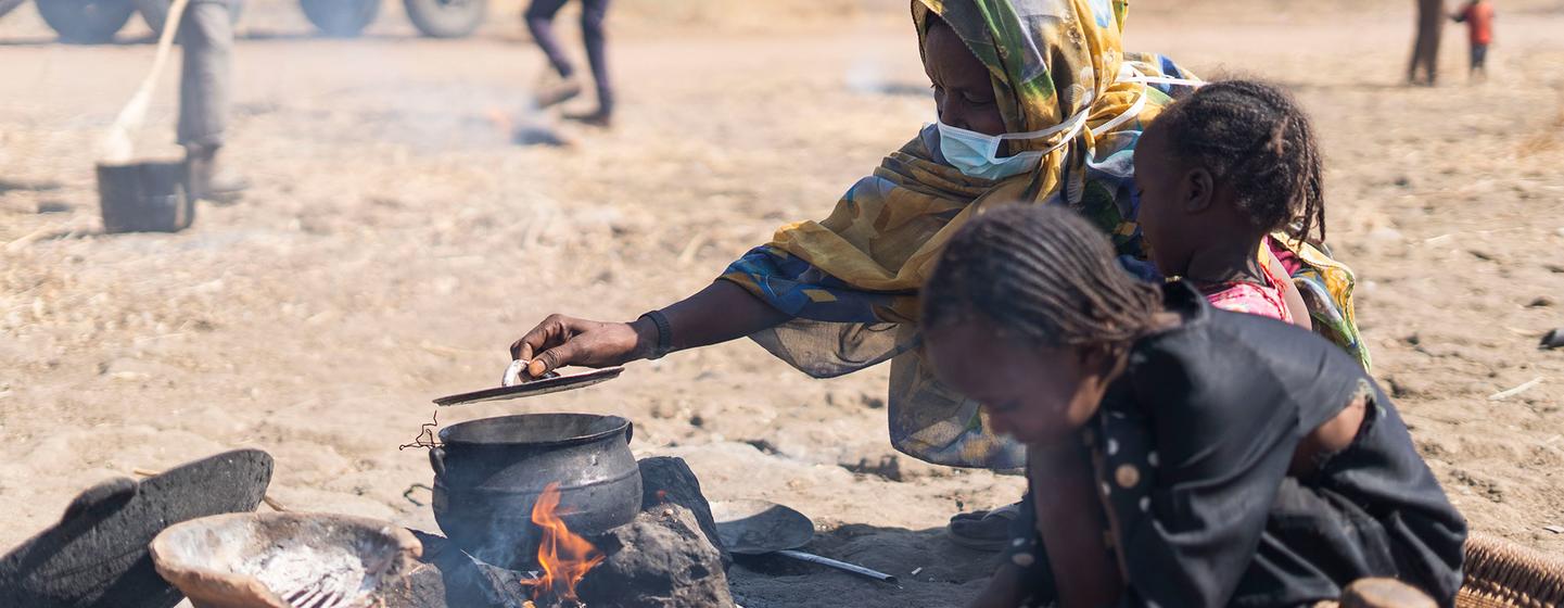Une femme déplacée à l'intérieur du pays cuisine dans un espace ouvert du camp d'El Ban Gadeed au Soudan. 