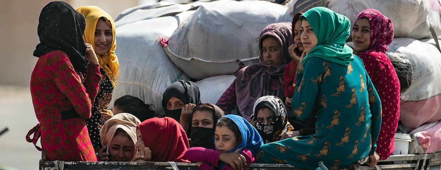 Des femmes et des enfants sont transportés à l'arrière d'un camion alors que des familles déplacées arrivent à Tal Tamer, en Syrie.