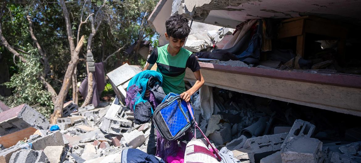 A boy picks through his belongings in the remains of his destroyed home in Gaza.