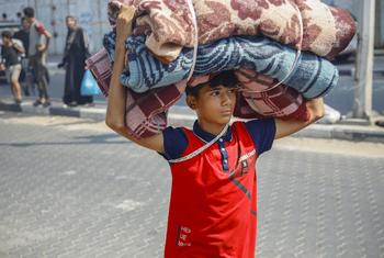 Un garçon porte des couvertures vers un refuge temporaire à Gaza.