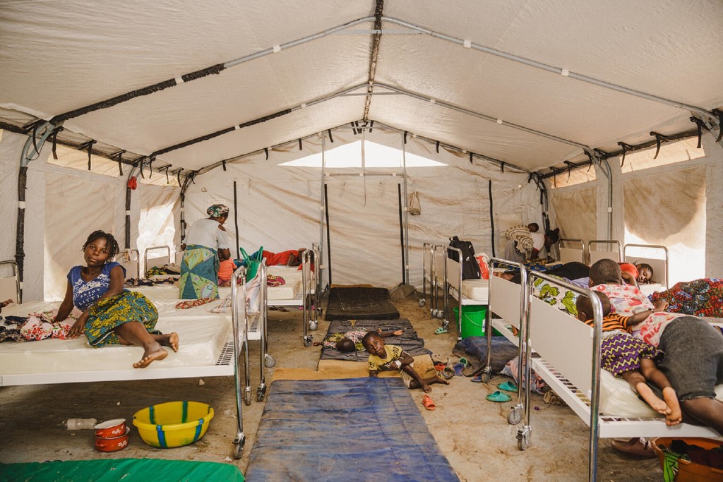 À l'intérieur d'une unité d'isolement mpox soutenue par l'UNICEF à l'hôpital de Kavumu, au Sud-Kivu, en République démocratique du Congo, des patients, dont des enfants, se reposent sur des lits et des nattes à l'intérieur d'une grande tente médicale.