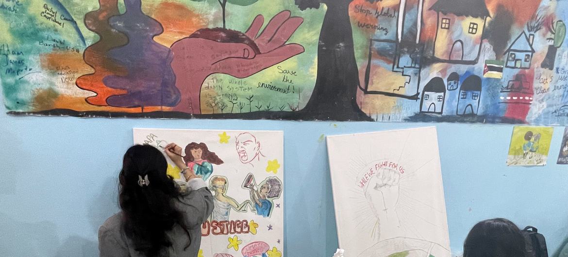 A defensora da juventude do Unicef, Ayshka Najib, pinta uma obra de arte colaborativa no pavilhão da juventude