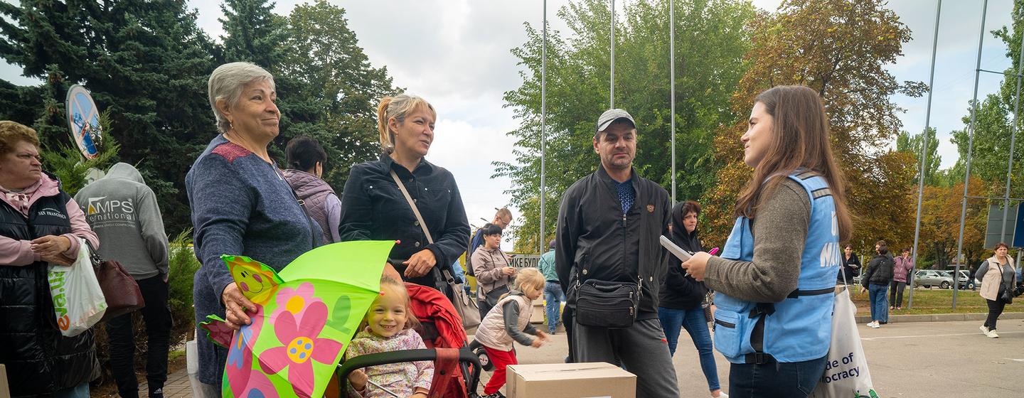 Une travailleuse humanitaire donne des informations à une famille qui arrive à un centre humanitaire à Zaporizhzhia, après avoir été évacuée de l'oblast de Donetska, en Ukraine, en 2022. 