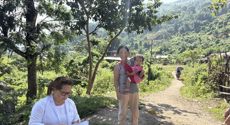 एक सत्र के दौरान, सहायक नर्स मिडवाइफ़, बच्चे के टीकाकरण कार्ड की जाँच करती हुई.