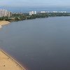 Vista panorâmica de uma praia de areia às margens de um grande rio em Manaus, Brasil, com edifícios altos ao fundo.