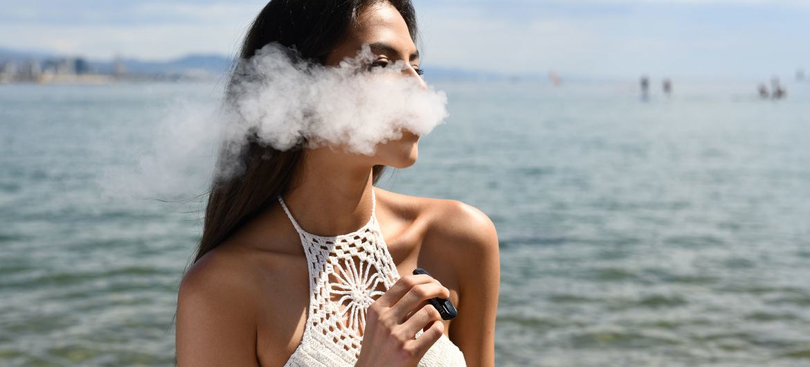 A woman smokes an e-cigarette. 