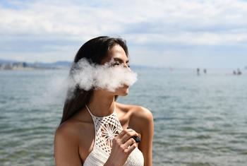 A woman smokes an e-cigarette. 