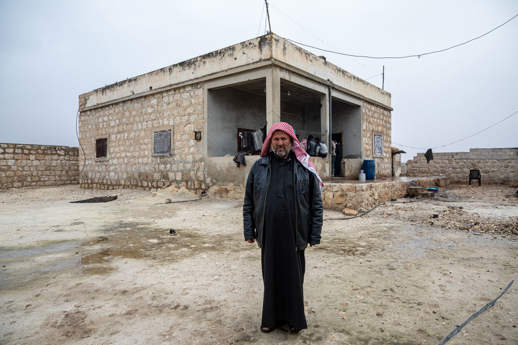 Picha ya Abd Alhameed Al-Hashimi, mwenye umri wa miaka 51, akiwa amesimama mbele ya nyumba yake katika kijiji cha Barneh, kusini mwa vijijini mwa Aleppo, baada ya kupokea kifurushi cha hifadhi kutoka UNHCR.