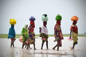 Unas mujeres cruzan una masa de agua en Rann, estado de Borno, Nigeria.