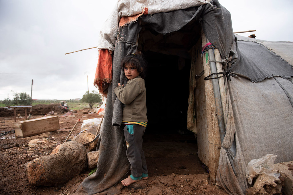 ایک سات سالہ بچی جنوبی شام میں واقع پناہ گزینوں کے ایک عارضی کیمپ میں اپنے ماں باپ کے ساتھ سر چھپائے ہوئے۔