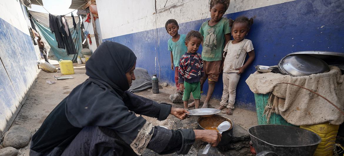 A mother-of-nine, who is suffering from malnutrition herself, cooks a meal for her children in an IDP camp in Aden, Yemen.