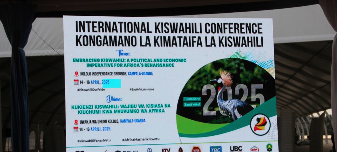 Mtazamo wa jukwaa katika Mkutano wa Kimataifa wa Kiswahili jijini Kampala, Uganda, ukiwa na bango kubwa linaloonyesha maelezo ya tukio na mada.