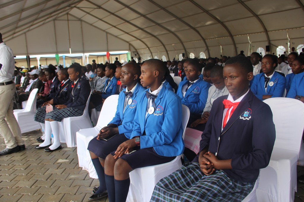 Wanafunzi waliovaa sare za shule wameketi katika hadhira katika mkutano wa Kiswahili nchini Uganda.