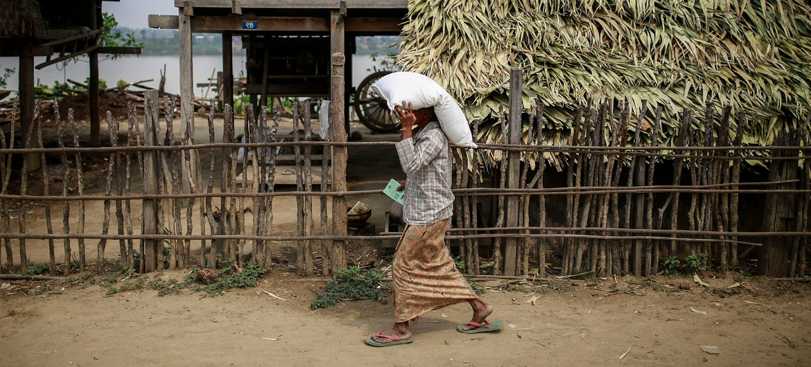 میانمار کے ایک گاؤں میں خاتون اقوام متحدہ کی طرف سے ملنے والی کھاد کی بوری لے کر جا رہی ہے۔