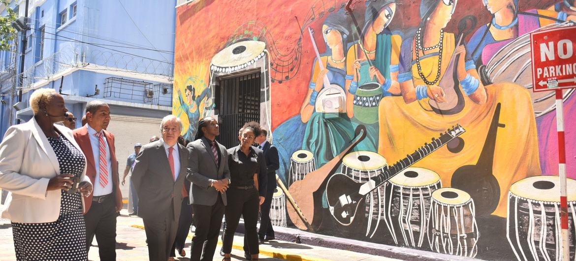 دبیر کل آنتونیو گوترش (سومین سمت چپ) آثار هنری پر جنب و جوشی که در Art Walk، Water Lane در مرکز شهر کینگستون در طول بازدید رسمی خود از جامائیکا به نمایش گذاشته شده است را تحسین می کند.