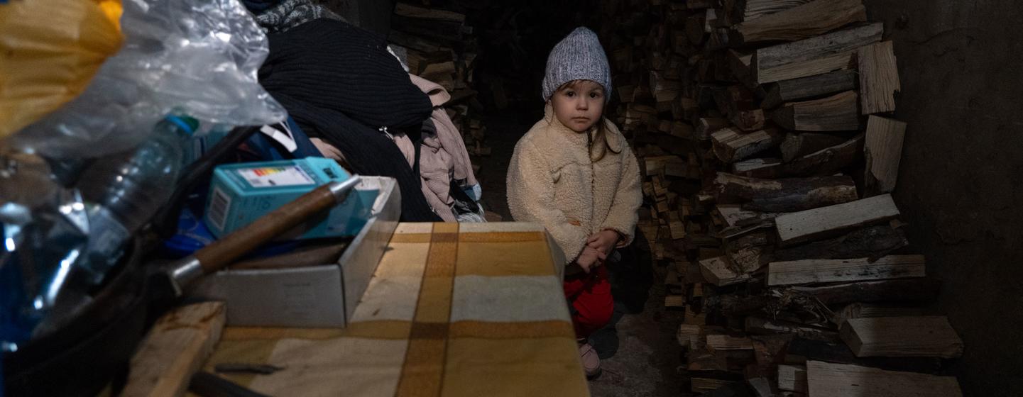 Uma menina de três anos é forçada a se abrigar do bombardeio em curso com sua família em um porão escuro e úmido em Lyman, Ucrânia