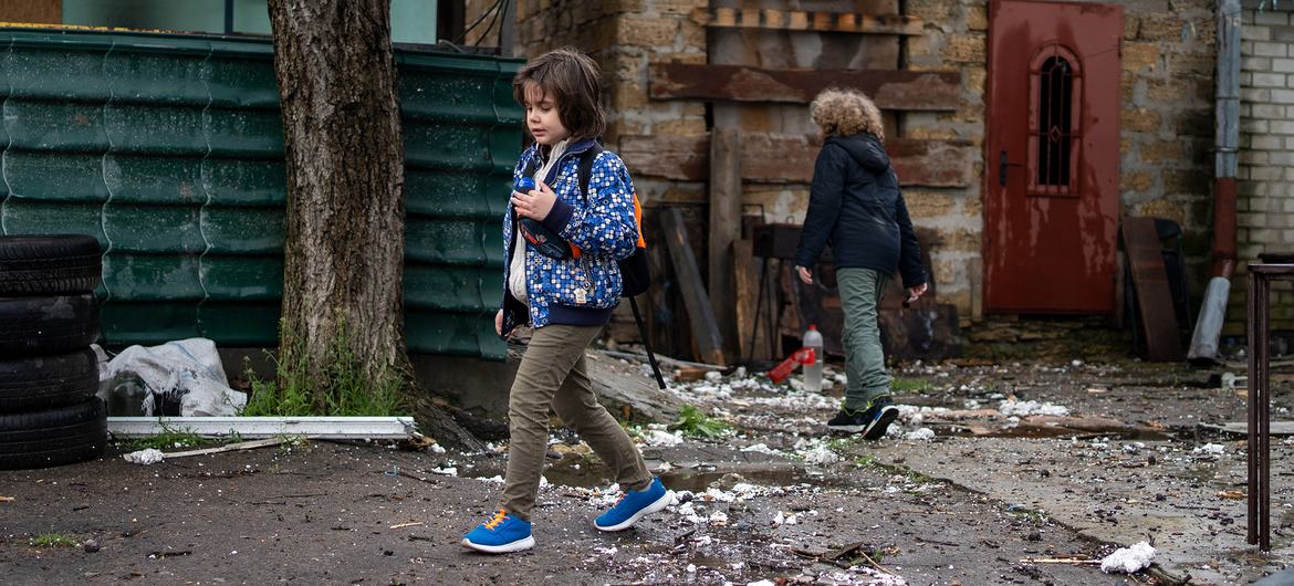 乌克兰赫尔松的孩子们走过一座被摧毁的房屋。