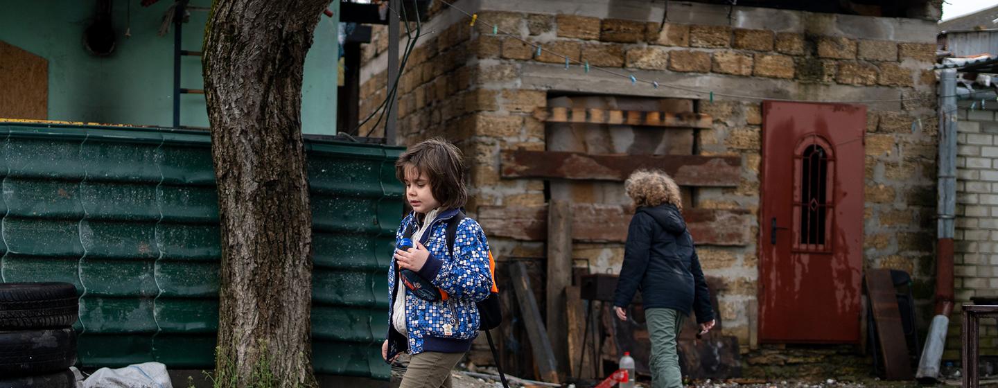 Des enfants passent devant une maison détruire à Kherson, en Ukraine.
