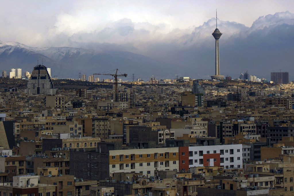 A view of the city of Tehran, Iran, with the Milad Tower and mountains in the background.