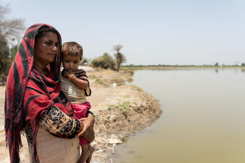 Benaziz, 30 ans, se tient avec sa fille Oumara, 3 ans, à côté des eaux stagnantes qui subsistent plus de 6 mois après les inondations dévastatrices de 2022.