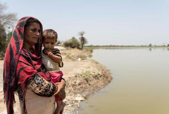 Benaziz, de 30 años, junto a su hija, Oumara, de 3, junto al agua estancada que aún permanece más de 6 meses después de las devastadoras inundaciones de 2022 en Pakistán.