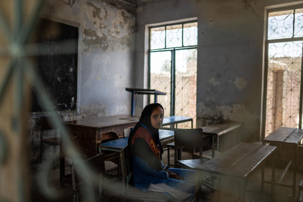 Uma menina paquistanesa de 10 anos chamada Bushra está sentada sozinha em uma sala de aula degradada e danificada por inundações em Basti Shahnawaz, distrito de Rajanpur, Punjab, Paquistão.