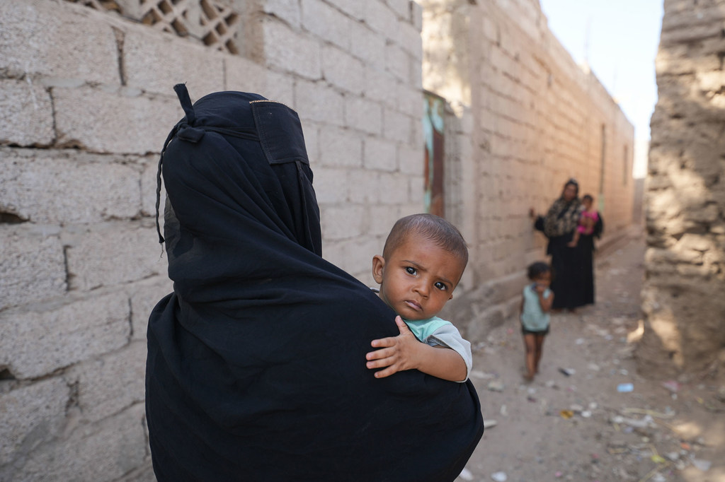 A young boy is carried by his mother thorough their neighbourhood in Al Hawtah, Lahj Governate in Yemen.
