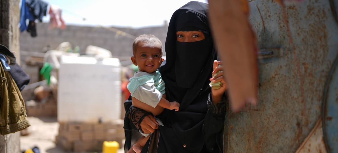 A mother holds her child near their home in the Al Adani neighbourhood of Al Hawtah, Yemen.
