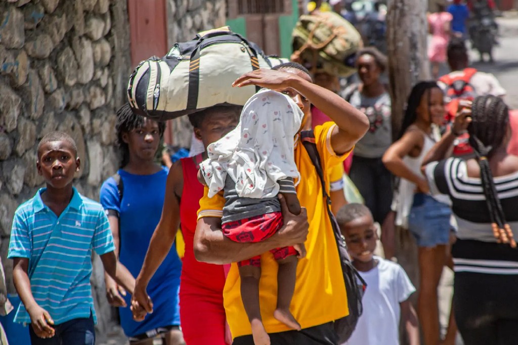 Desplazadas por la escalada de violencia, las familias de Haití cargan con sus pertenencias mientras huyen de sus hogares en busca de seguridad.