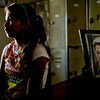 Una niña está sentada en un albergue en Reynosa, México, con una imagen de la Virgen María sobre una mesa a su lado.