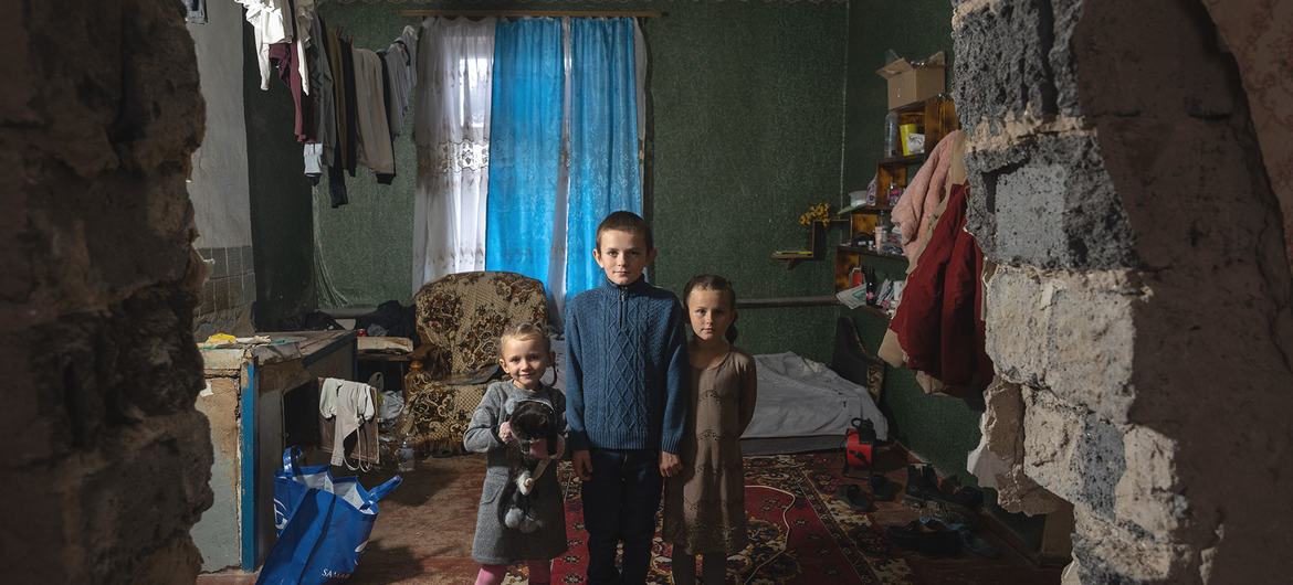 Tres hermanos ucranianos vestidos con ropa provista por UNICEF.