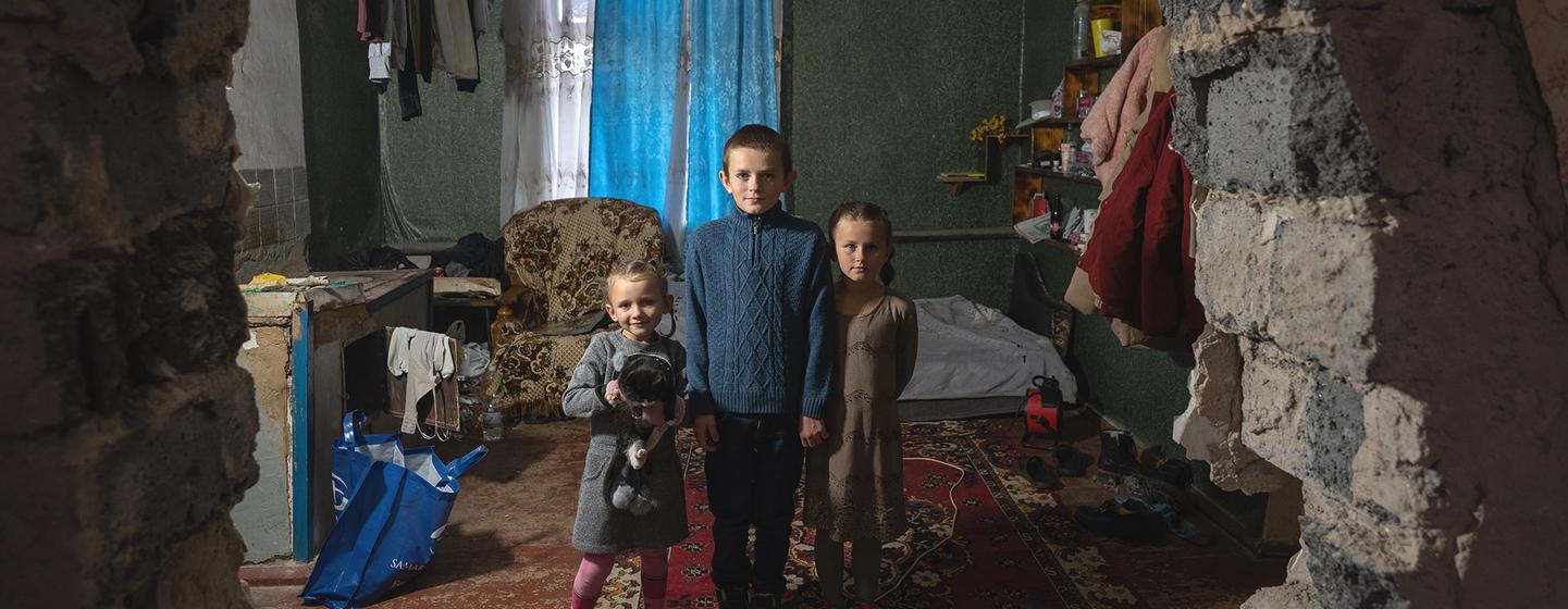 Three siblings pose in clothes provided by UNICEF.