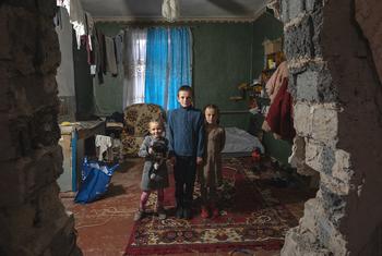 तीन भाई-बहन, यूनीसेफ़ द्वारा उपलब्ध कराए गए कपड़ों में फोटो खिंचा रहे हैं