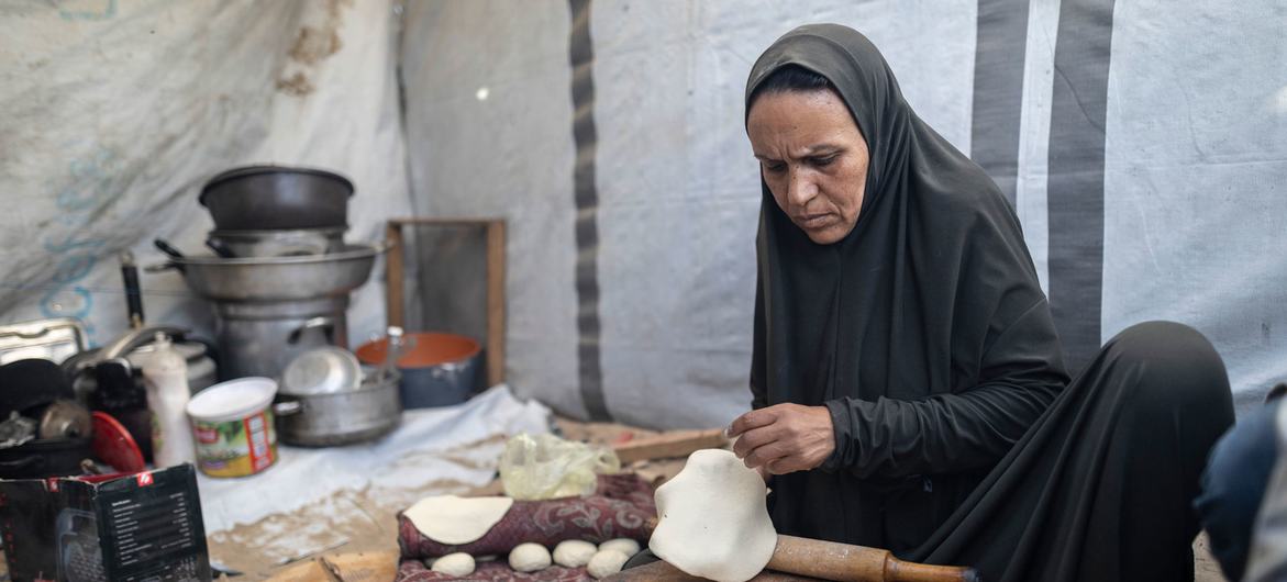 Une femme prépare du pain dans sa tente à Gaza.