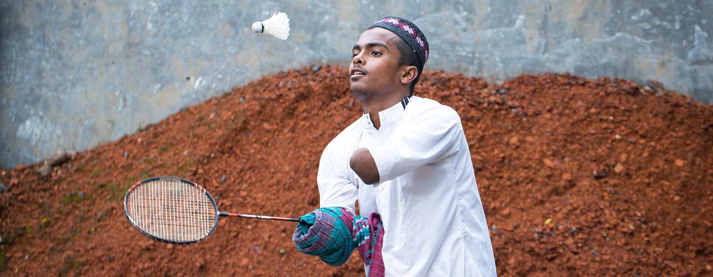 A disabled teenage boy plays badminton in front of his house in Bangladesh.