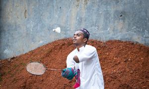 A disabled teenage boy plays badminton in front of his house in Bangladesh.