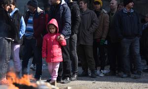 A girl and her father wait in line to receive aid items at a shelter in southeastern Türkiye.