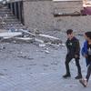 दो लड़के काहारनमारास, तुर्कीये में भूकम्प से क्षतिग्रस्त सड़कों से गुज़रते हुए.