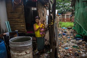 A woman holds her six-month-old son in front of their small makeshift home in Yangon, Myanmar.