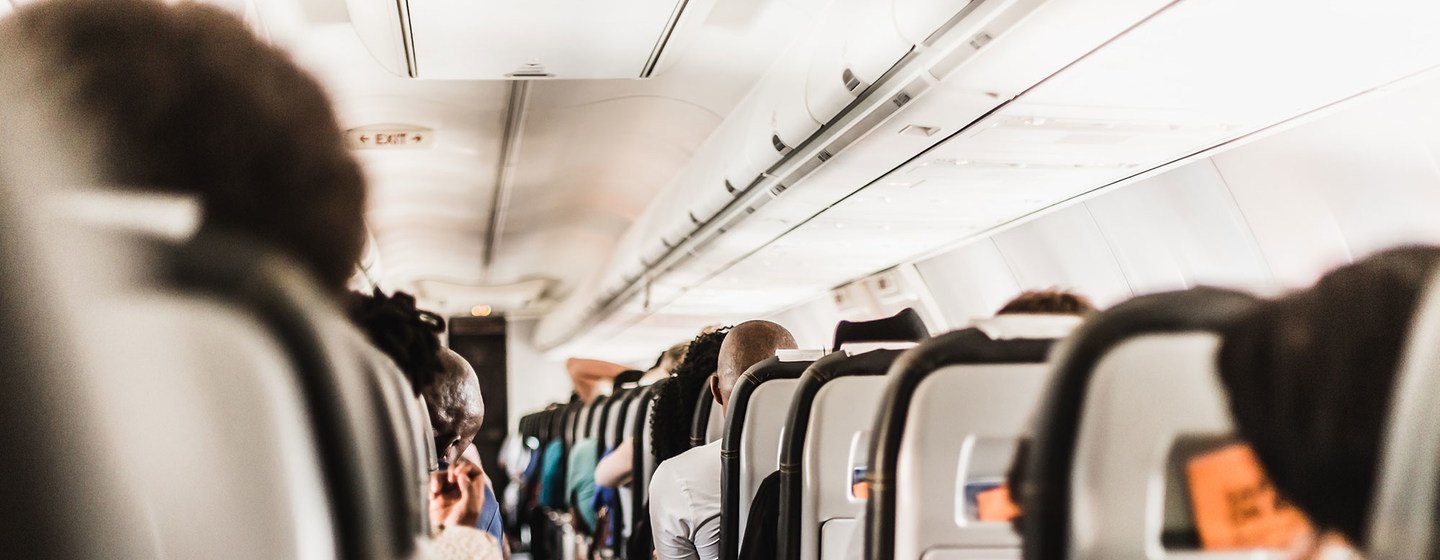 Vue en bas de l'allée d'une cabine d'avion avec des passagers assis.