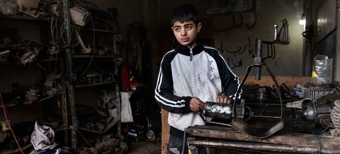 صبي يبلغ من العمر 13 عامًا يعمل في ورشة ميكانيكي في سوريا.