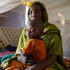 सूडान में जारी युद्ध के हालात में, दारफ़ूर में यूनीसेफ़ समर्थित स्वास्थ्य केन्द्र में एक महिला अपने बच्चे के साथ.