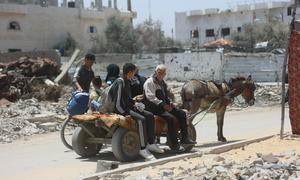 Una familia desplazada viaja en un carro tirado por un burro cargado con sus pertenencias.