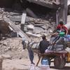 A displaced family travels on a donkey-pulled cart carrying their belongings.