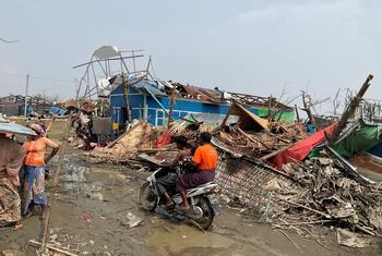 在缅甸若开邦首府实兑，几名男子骑着摩托车穿过被气旋破坏的泰昌境内流离失所者营地