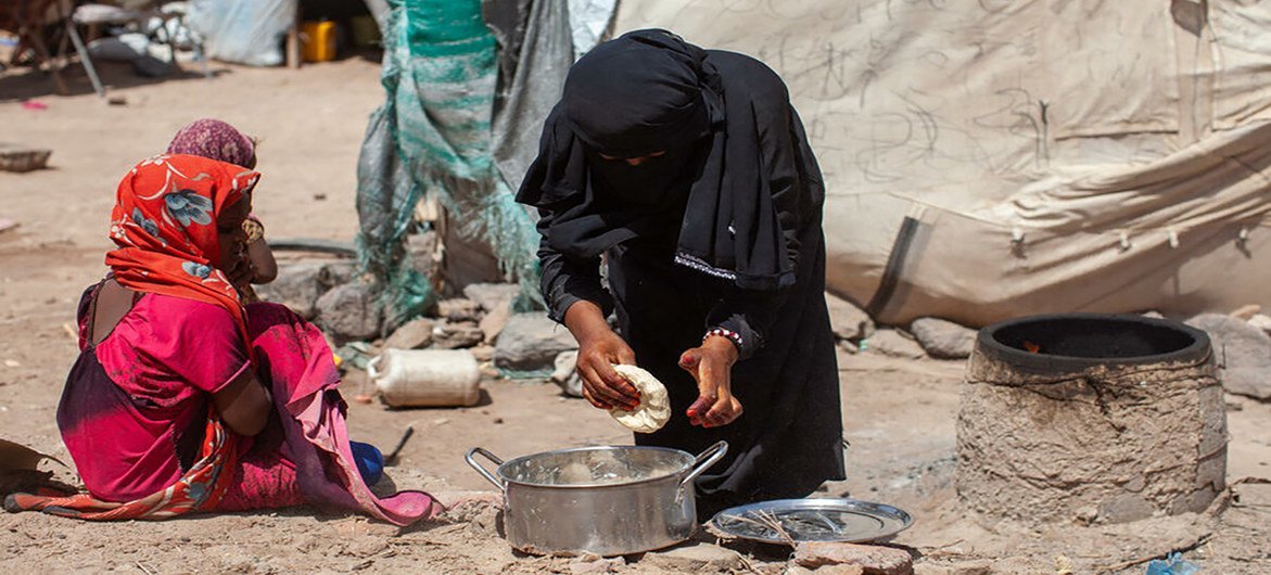 在也门，7 岁的卡里玛看着母亲哈亚特做面包。