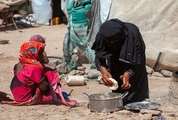 在也门，7 岁的卡里玛看着母亲哈亚特做面包。