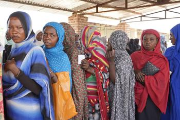 نساء ينتظرن في الطابور لتلقي المساعدات النقدية في السودان.
