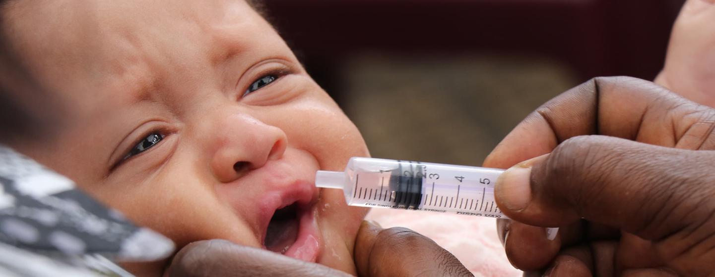 En République démocratique du Congo, un agent de santé administre un médicament par voie orale à un nourrisson à l'aide d'une seringue.