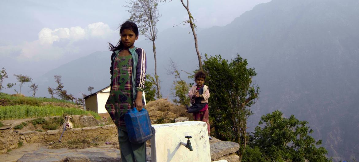 A young girl stands next to a tap with a small jerry can in a mountain village in Nepal. Many houses lack piped water, so children often fetch water on their way home from school. A young girl stands next to a tap with a small jerry can in a mountain village in Nepal. Many houses lack piped water, so children often fetch water on their way home from school.